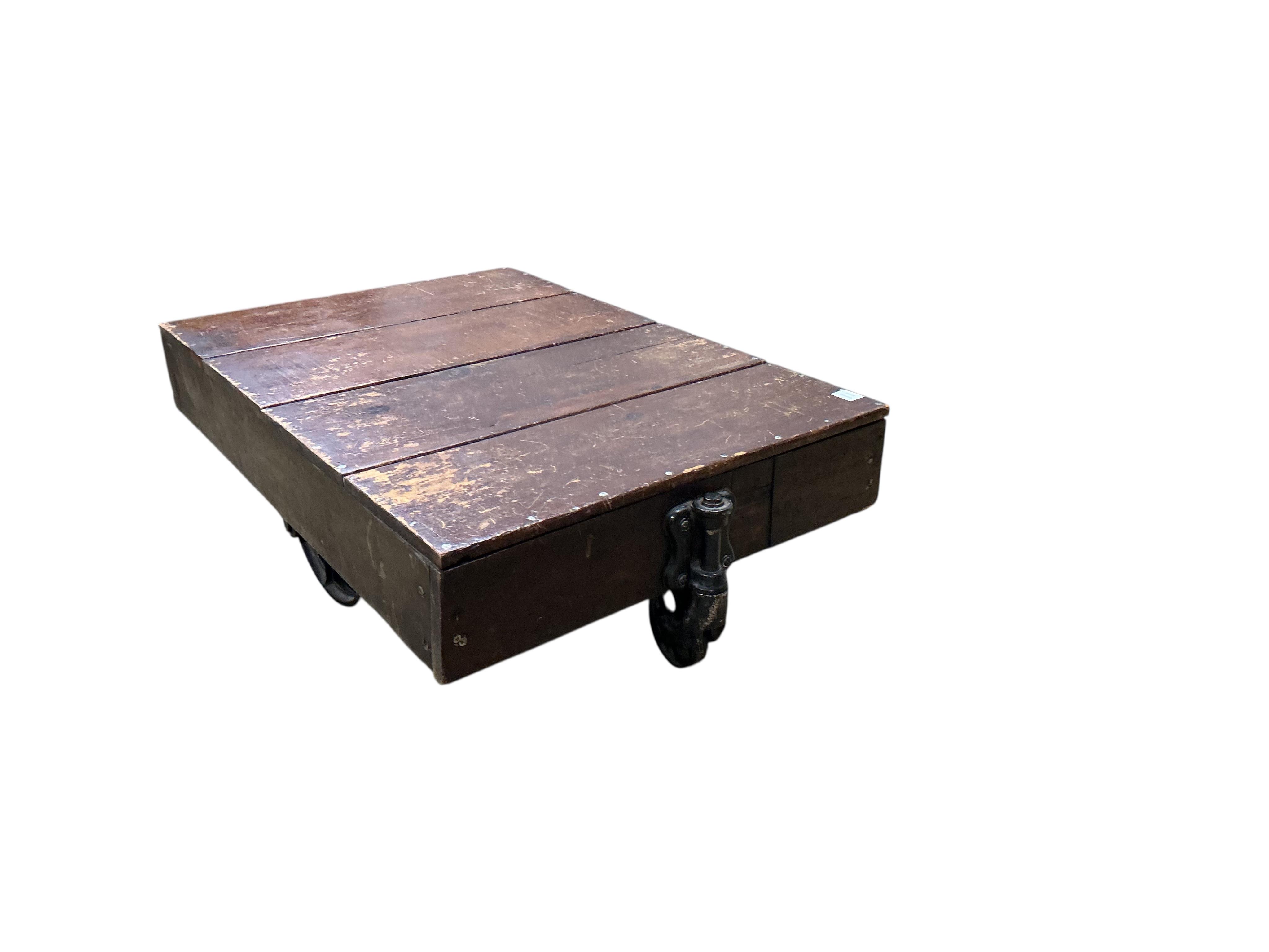 A vintage rectangular wood factory cart with iron spoked wheels now as a coffee table, width 112cm, depth 76cm, height 35cm